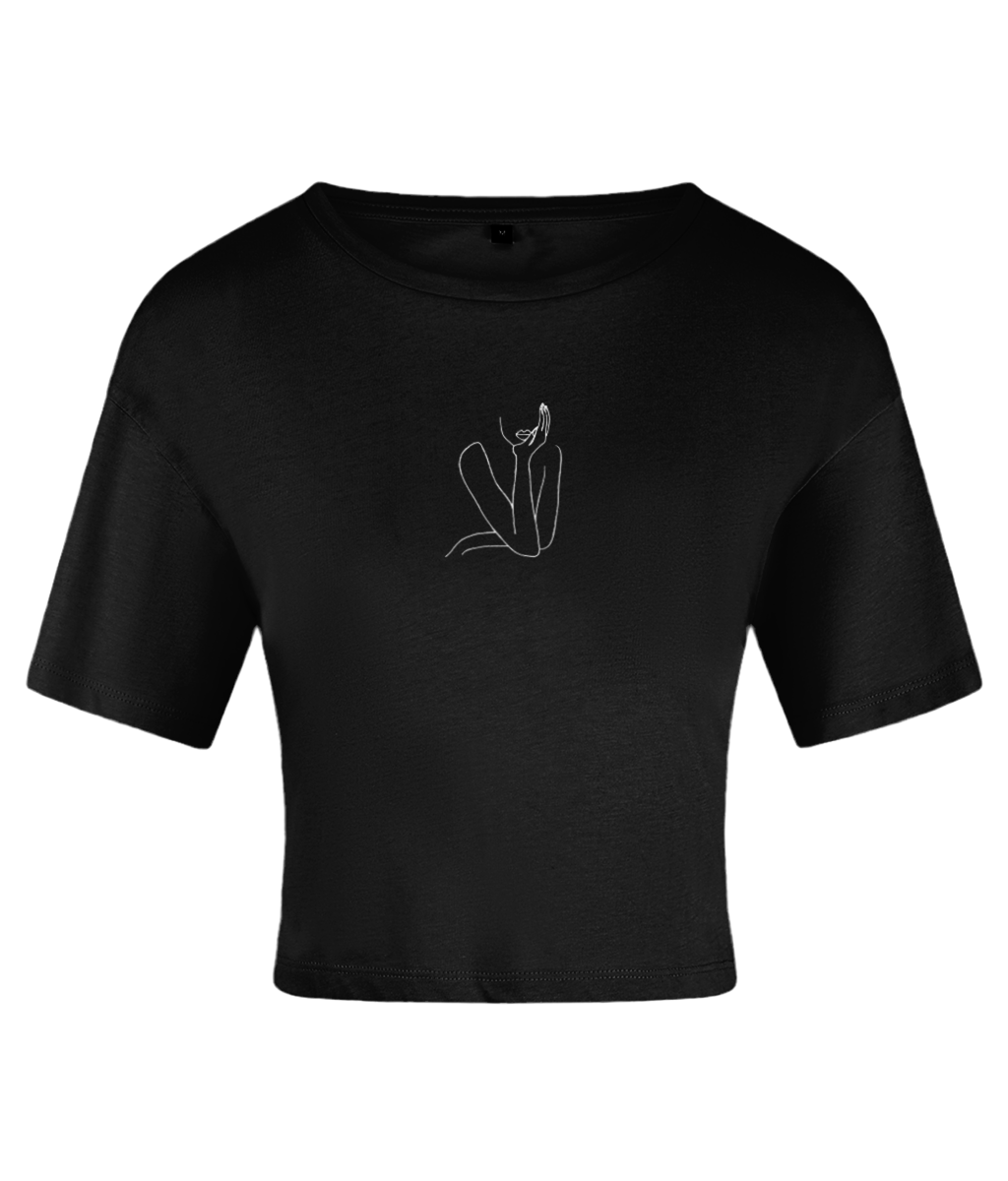 A black crop top with a crew neckline and short sleeves, featuring a sketch-style line art of a figure on the front. On a white backdrop.
