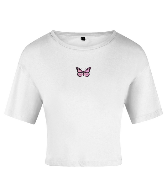 A white crop top with a pink butterfly graphic on the chest area, featuring short sleeves and a crew neckline. On a white backdrop.